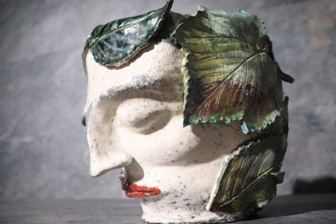 Scultura creata di ceramica artistica raku vaso con ritratto umano ricoperto di foglie